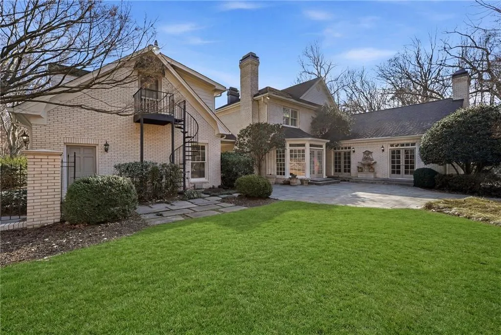 Back of property with a yard, a chimney, a balcony, a patio area, and brick siding