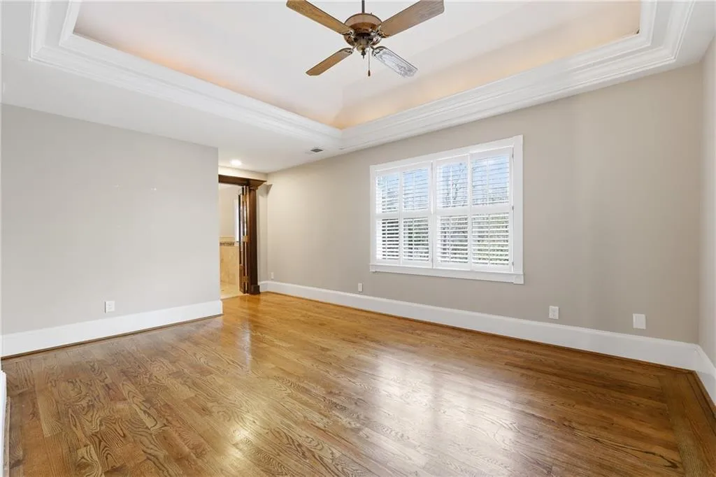 Spare room with light wood-type flooring, a ceiling fan, ornamental molding, and a tray ceiling