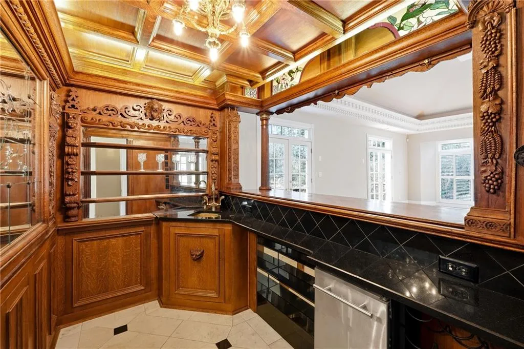 Kitchen featuring crown molding, wood finish cabinets, dark countertops, coffered ceiling, and healthy amount of natural light