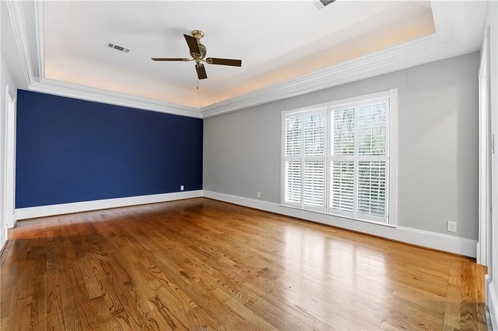 Unfurnished room with a raised ceiling, light wood-type flooring, and ceiling fan