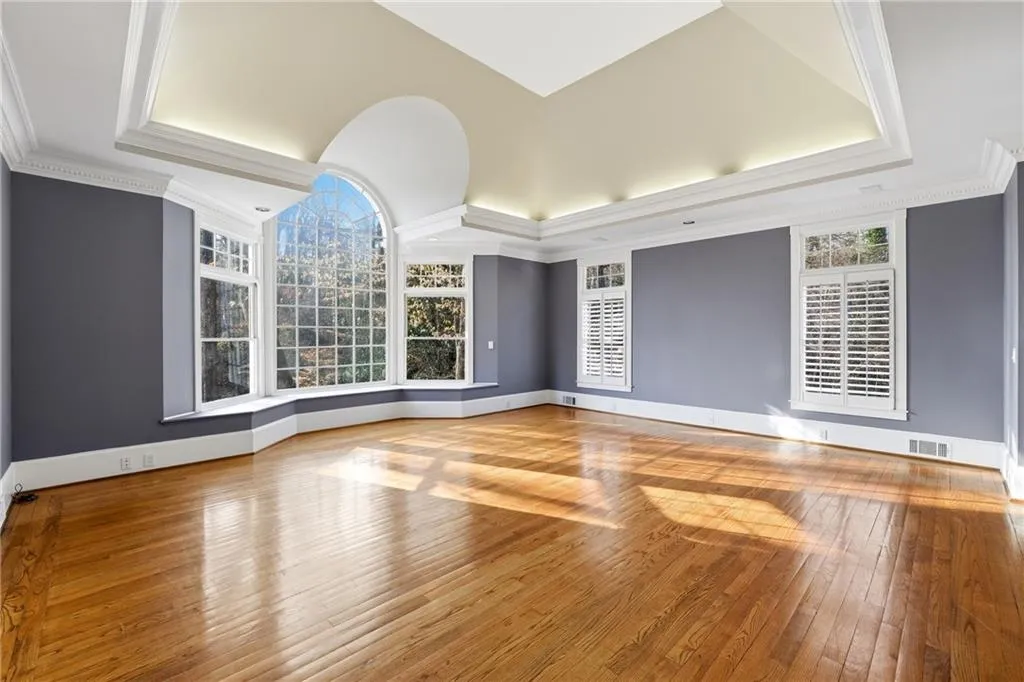 Unfurnished living room with hardwood / wood-style floors and crown molding