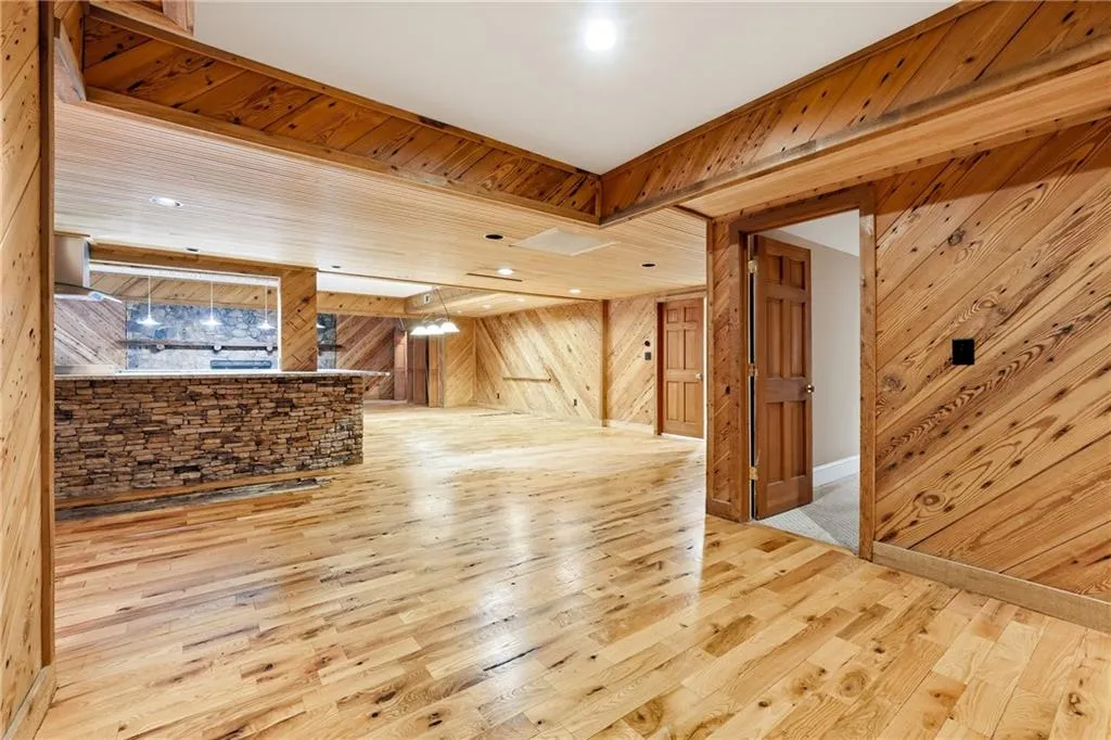 Unfurnished living room with light wood finished floors, wooden walls, and recessed lighting