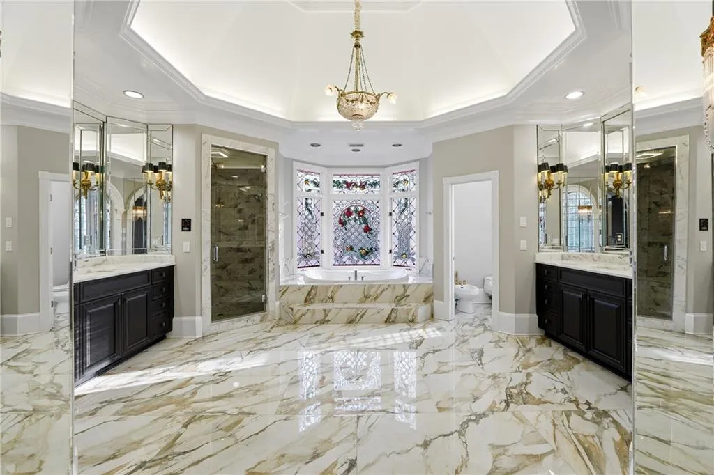 Bathroom featuring ornamental molding, suspended lighting, a marble finish shower, a bidet, and two vanities