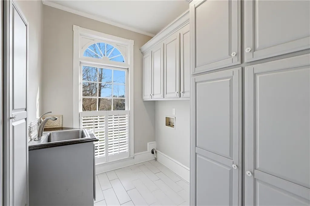 Laundry area featuring cabinet space, crown molding, and washer hookup