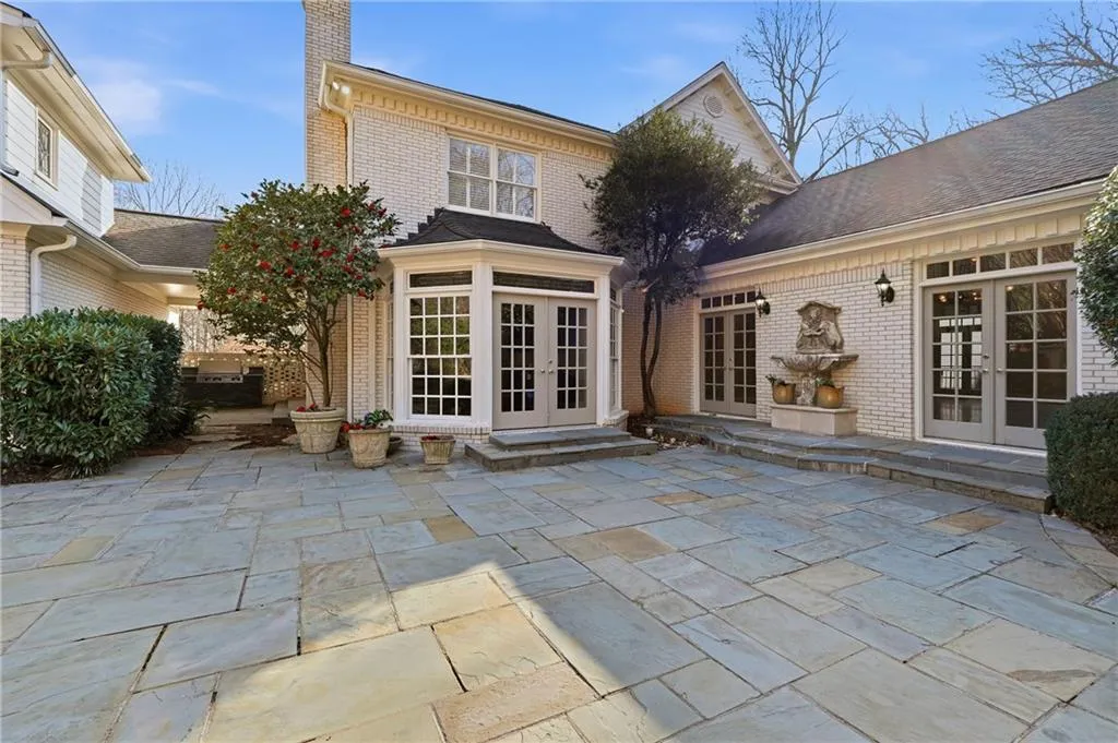 Back of house featuring french doors, a patio area, brick siding, and a chimney