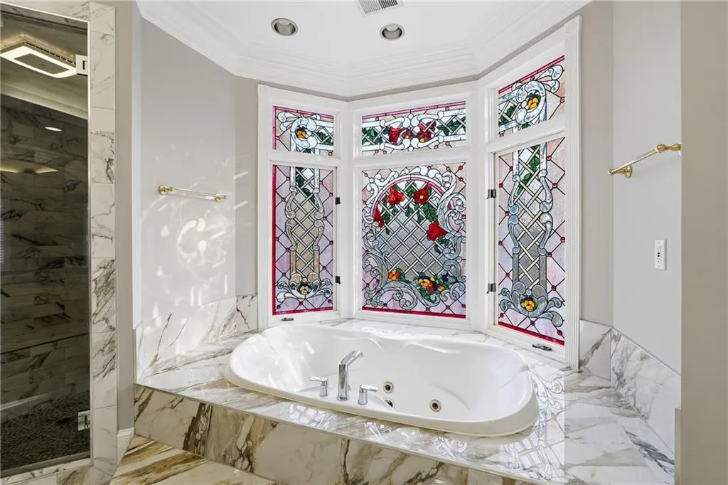 Bathroom featuring plenty of natural light, ornamental molding, a tub with jets, and a marble finish shower