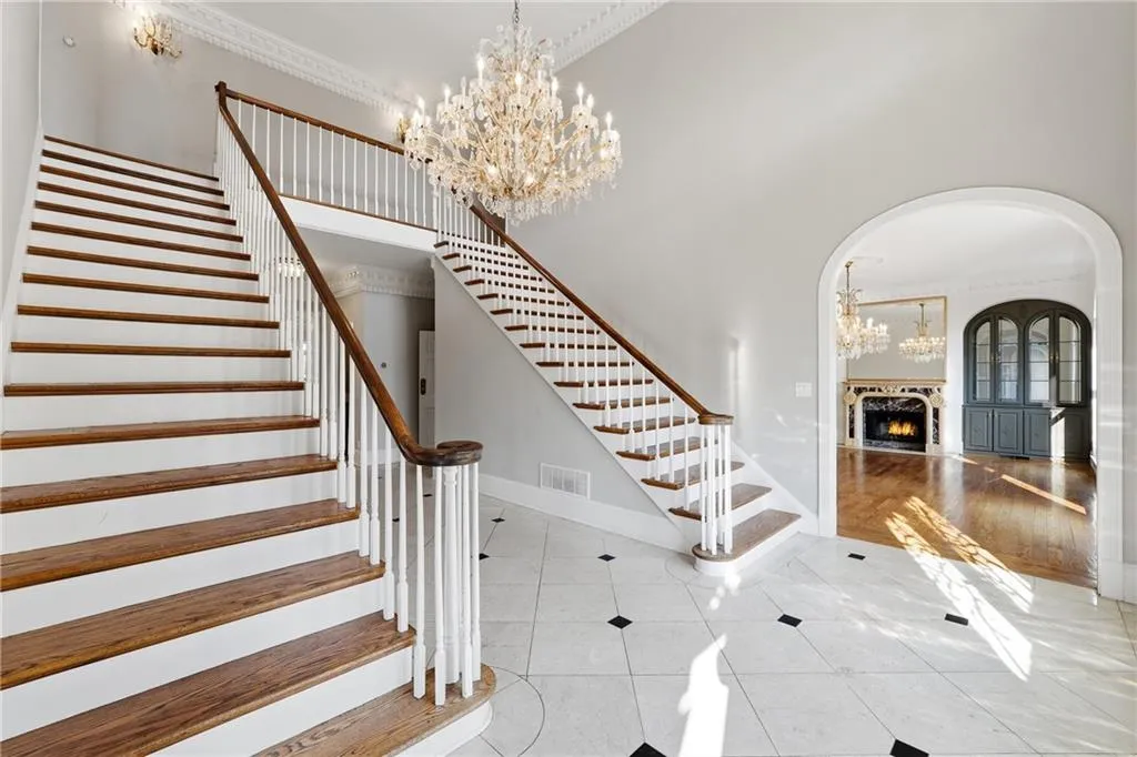 Staircase featuring suspended lighting, ornamental molding, a lit fireplace, a high ceiling, and tile patterned flooring