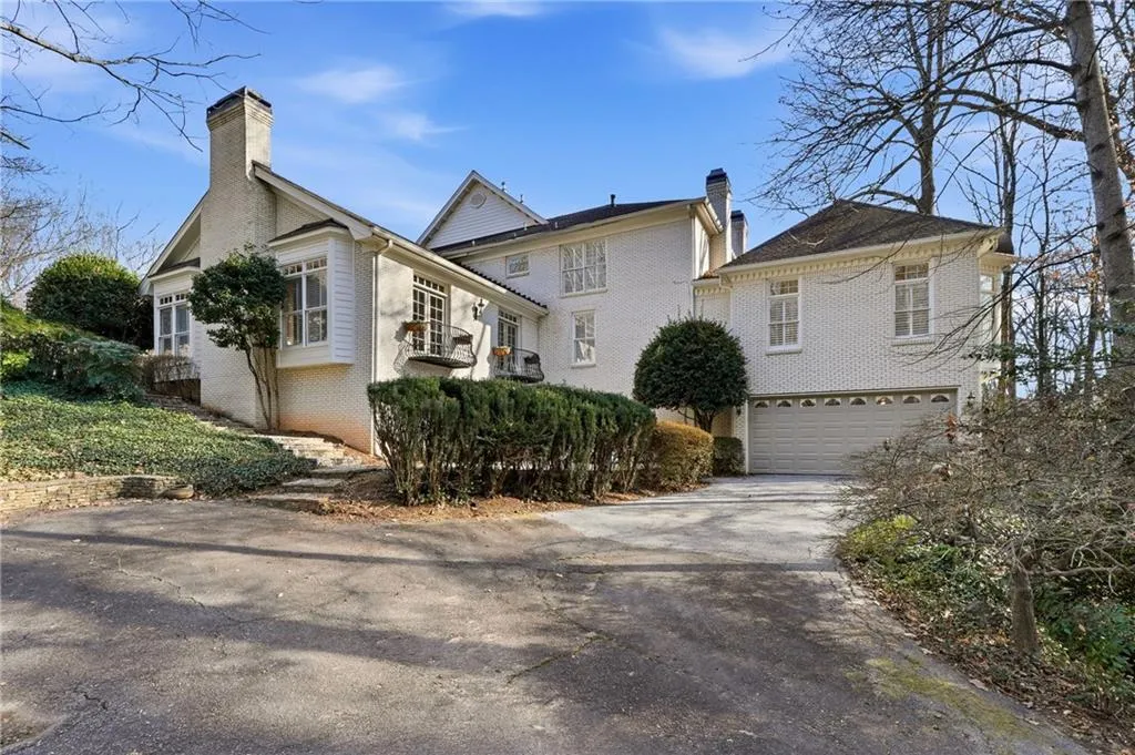 View of front of house featuring a chimney, brick siding, asphalt driveway, and a garage