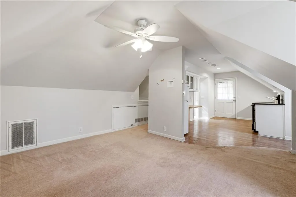 Bonus room featuring light colored carpet, lofted ceiling, and a ceiling fan