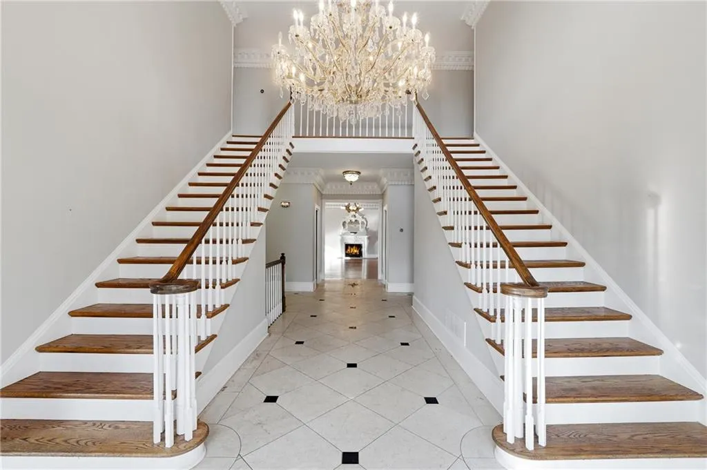 Stairs with suspended lighting, a high ceiling, a warm lit fireplace, ornamental molding, and tile patterned floors