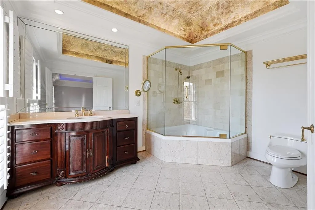 Full bathroom with ornamental molding, vanity, a tray ceiling, and tiled shower / bath combo
