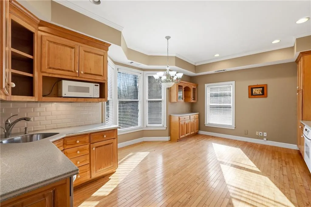 Kitchen featuring a chandelier, light wood-type flooring, white microwave, ornamental molding, and tasteful backsplash