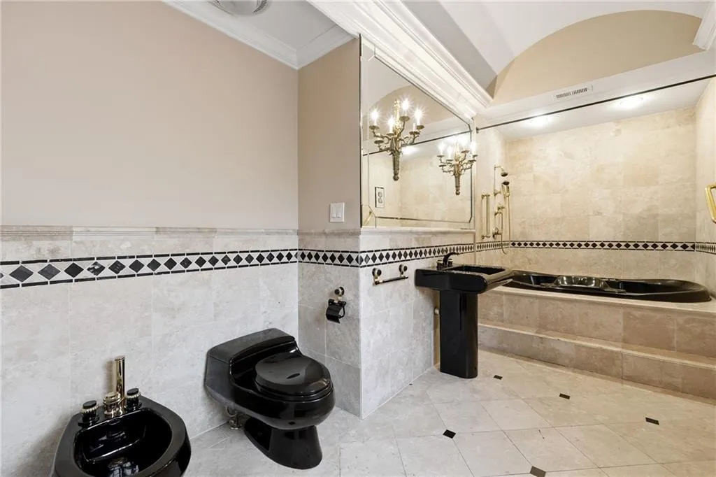 Full bathroom featuring a bidet, tile walls, light tile patterned floors, crown molding, and wainscoting