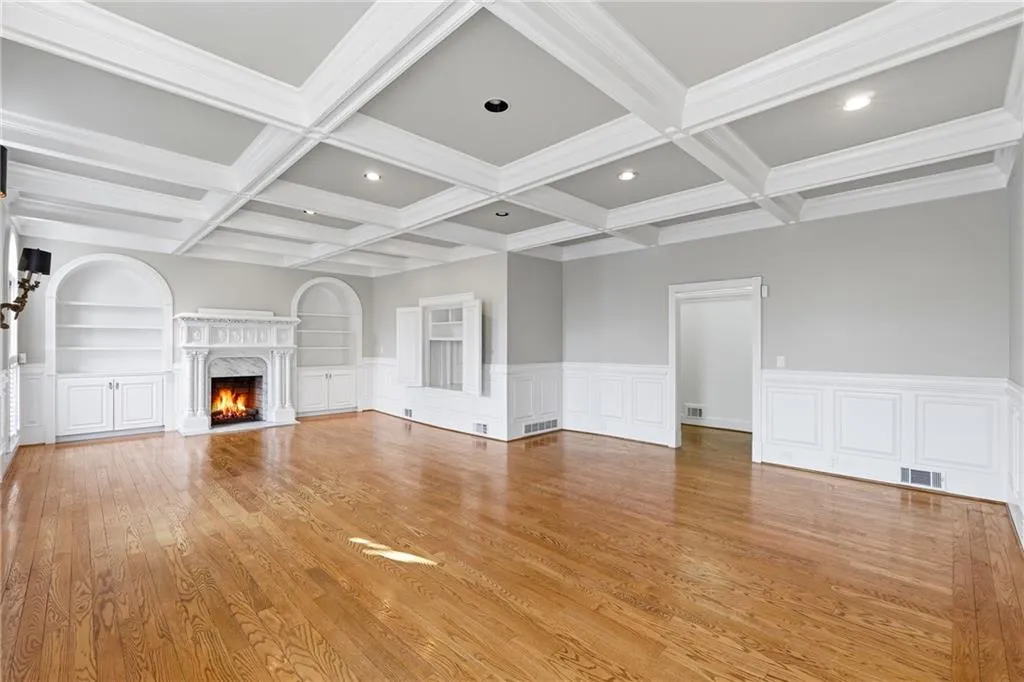 Unfurnished living room featuring built in features, a fireplace, coffered ceiling, light wood-style floors, and recessed lighting