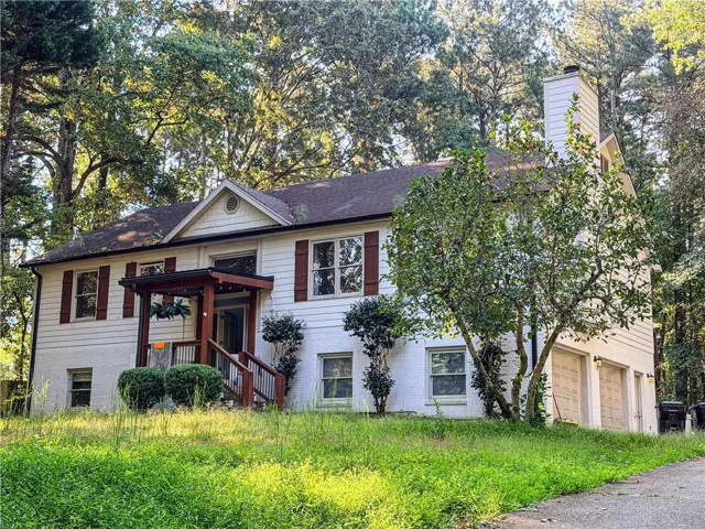 Two-story residence featuring white siding, a prominent front porch with wood-finish railings, and a side-entry two-car garage