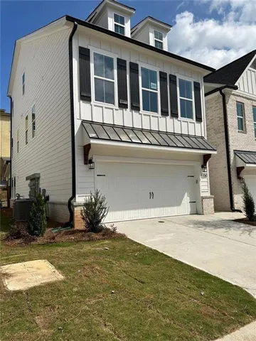 View of front of house with central AC unit, a garage, and a front yard