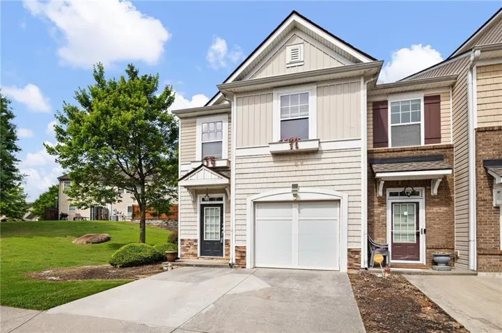 Two-story exterior with siding and stone accents, featuring a single-car garage, front entry door with transom window, and a window box planter