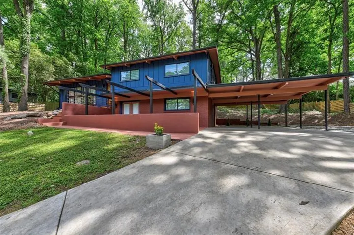 View of front of house with an attached carport, brick siding, board and batten siding, and driveway