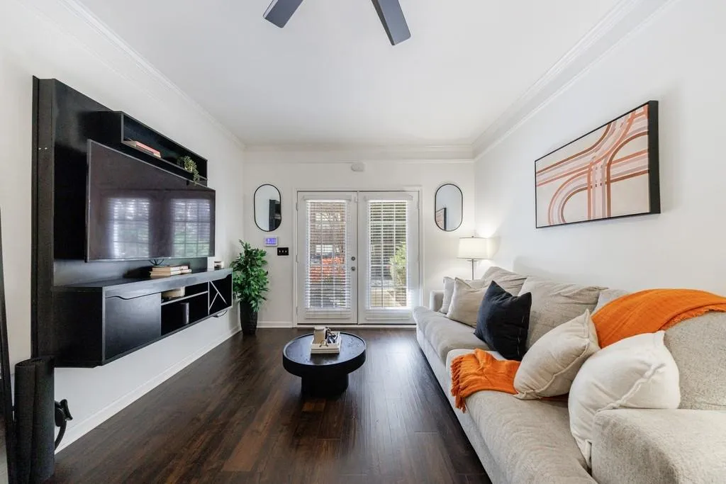 Living room with ornamental molding, dark hardwood / wood-style floors, ceiling fan, and french doors