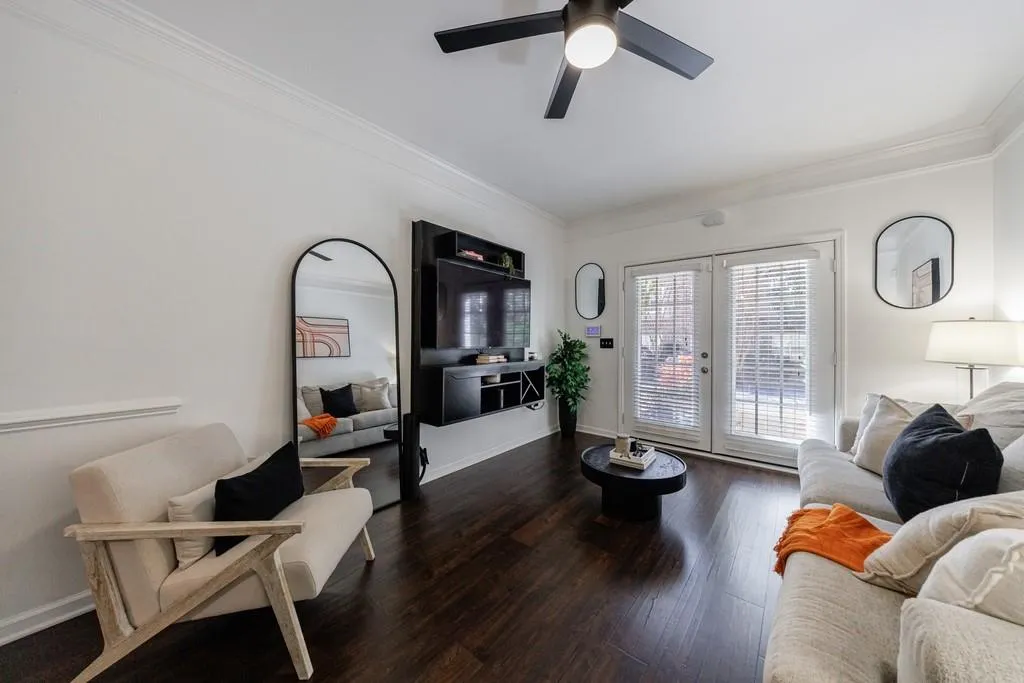Living room with dark wood-type flooring, ceiling fan, crown molding, and french doors