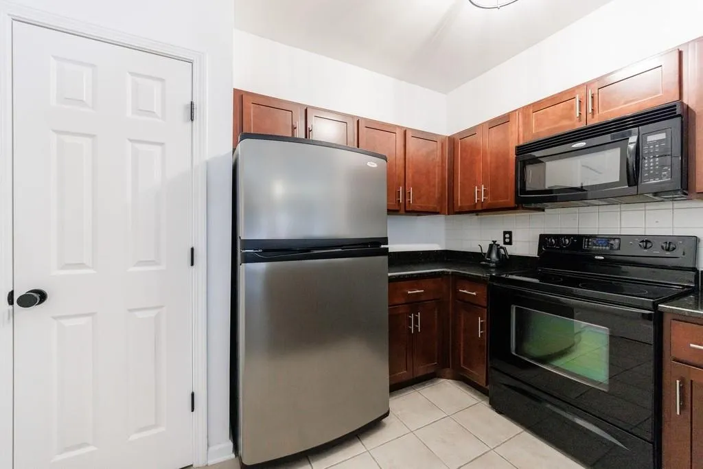 Kitchen featuring light tile patterned floors, decorative backsplash, and black appliances