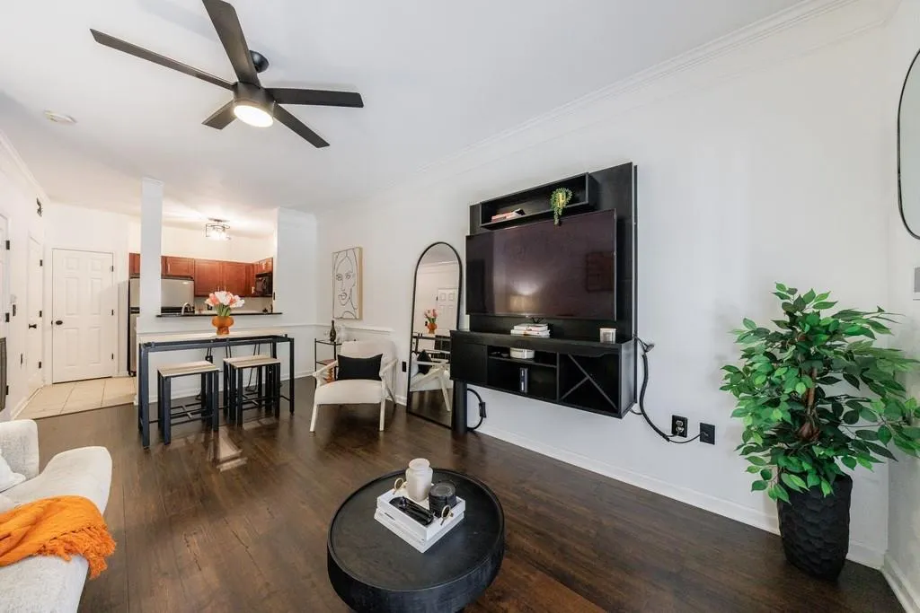 Living room with wood-type flooring, ornamental molding, and ceiling fan
