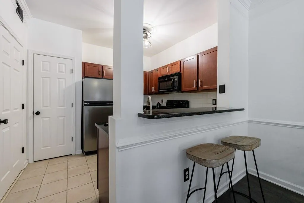Kitchen featuring stainless steel refrigerator, backsplash, a kitchen bar, light tile patterned floors, and kitchen peninsula
