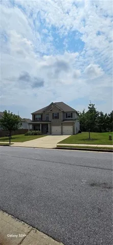 Two-story residence featuring a brick and siding exterior, a two-car garage, and a covered front porch