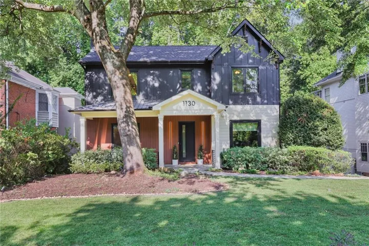 Two-story residence featuring a covered front porch, dark board and batten siding, light-colored horizontal siding, and a dark asphalt shingle roof