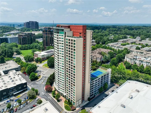 Contemporary high-rise building featuring a curved facade, rooftop deck, and a distinctive red top-level accent