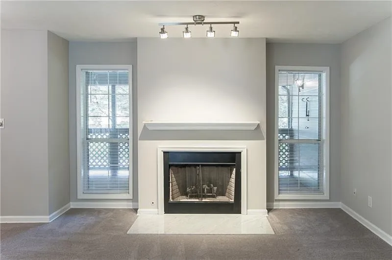 Detailed view of carpet flooring, a fireplace, and track lighting