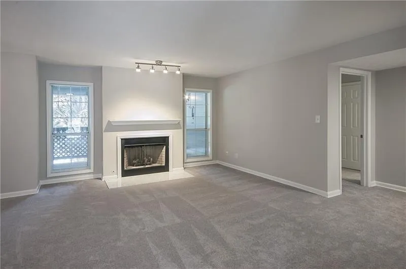 Unfurnished living room featuring carpet floors and a fireplace with flush hearth