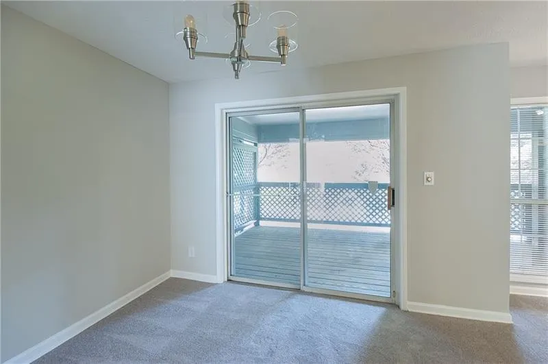 Carpeted spare room with a chandelier and baseboards