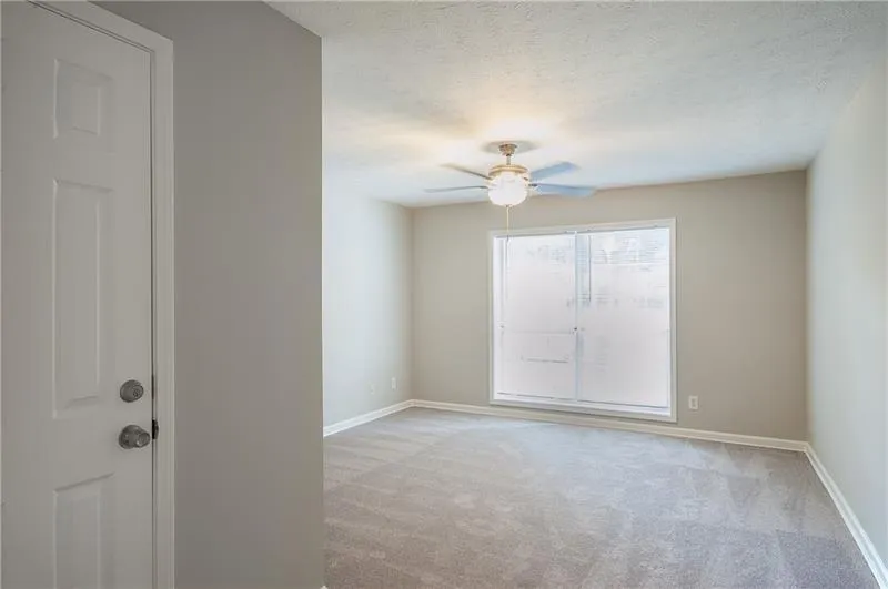 Empty room with light carpet, a ceiling fan, and a textured ceiling