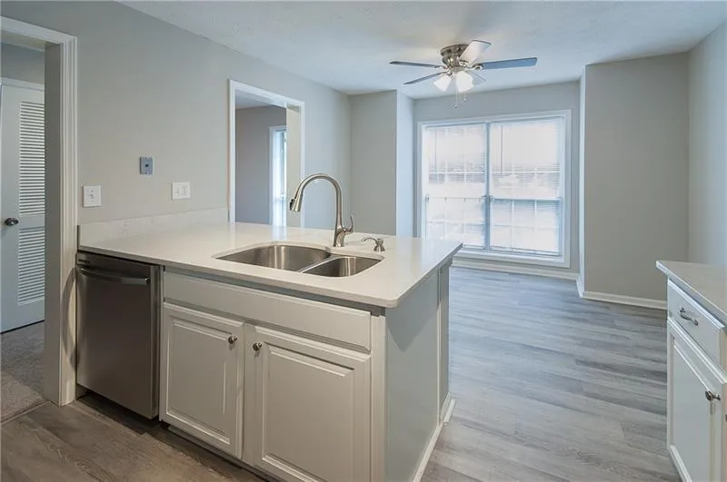 Kitchen featuring light wood-style floors, dishwasher, light countertops, ceiling fan, and a peninsula