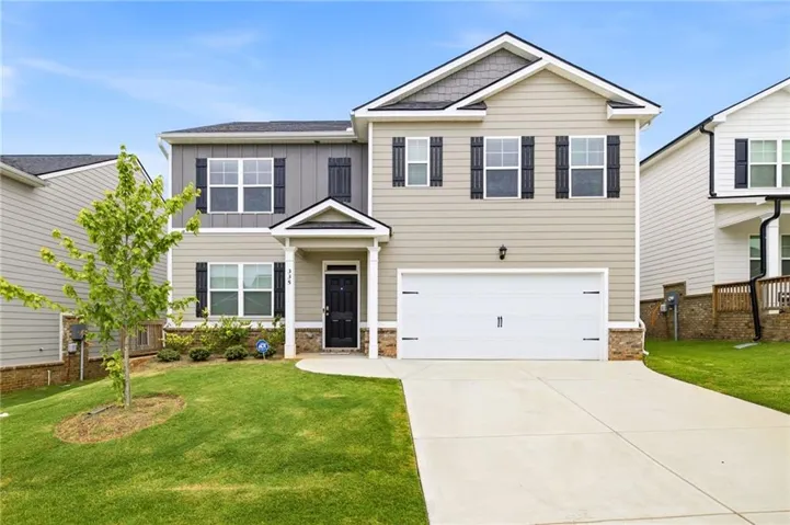 Two-story residence featuring light neutral siding, a dark gray vertical siding accent, and dark shutters