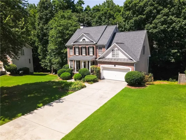 Brick and siding exterior with a gabled roofline and dark shutters