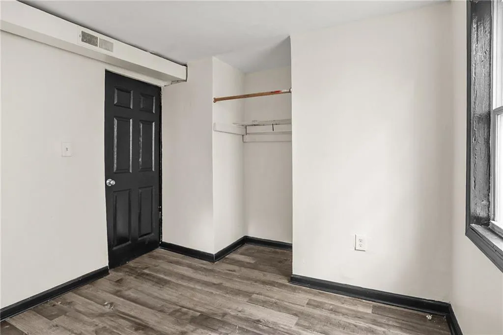 Unfurnished bedroom with dark wood-style flooring and a closet