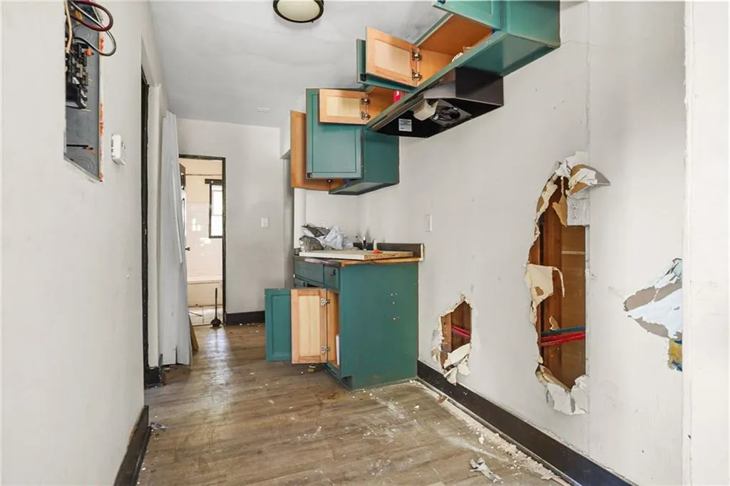 Kitchen with dark wood-type flooring, green cabinets, butcher block countertops, and electric panel