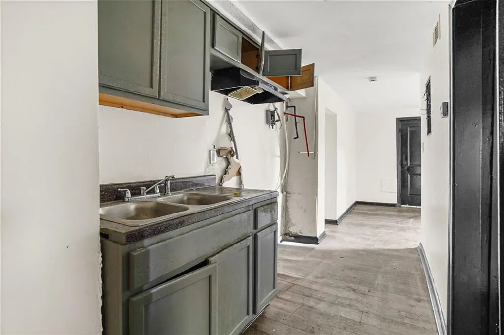 Kitchen featuring dark countertops, light wood-style floors, gray cabinets, and under cabinet range hood
