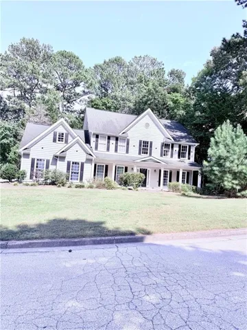 Traditional-style residence featuring light-colored siding, multiple gables, and black shutters
