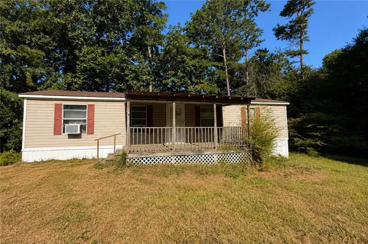 Exterior siding, covered porch with wood railings, and a sloped front yard