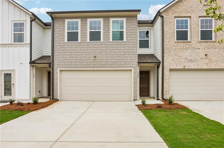 Contemporary townhome exterior featuring a two-car garage, mixed siding, and a dark wood-finish entry door