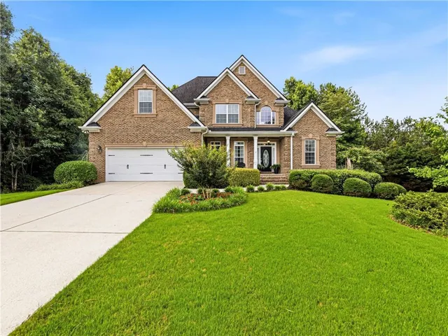 Traditional brick exterior featuring white trim, a two-car garage, and a covered portico entrance