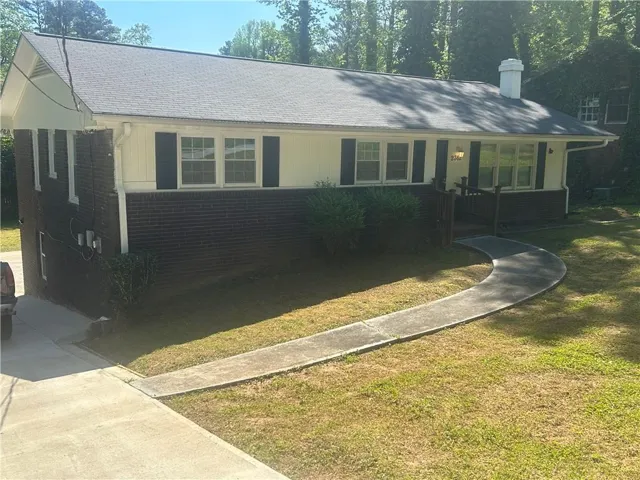 Brick and siding exterior with dark shutters, front porch with railings, and a curved concrete walkway