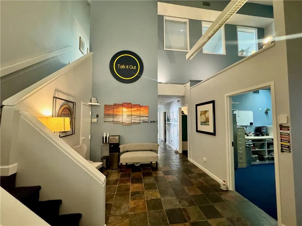 Reception with a towering ceiling, stairs, and tile stone floors