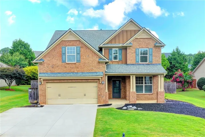 Brick Colonial two-story home featuring a welcoming front, elevation with peaked rooflines, multiple gabled sections, and substantial window placement throughout.