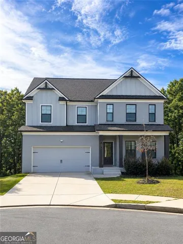 Two-story residence with a dark shingle roof, light-toned exterior siding, and a prominent two-car garage