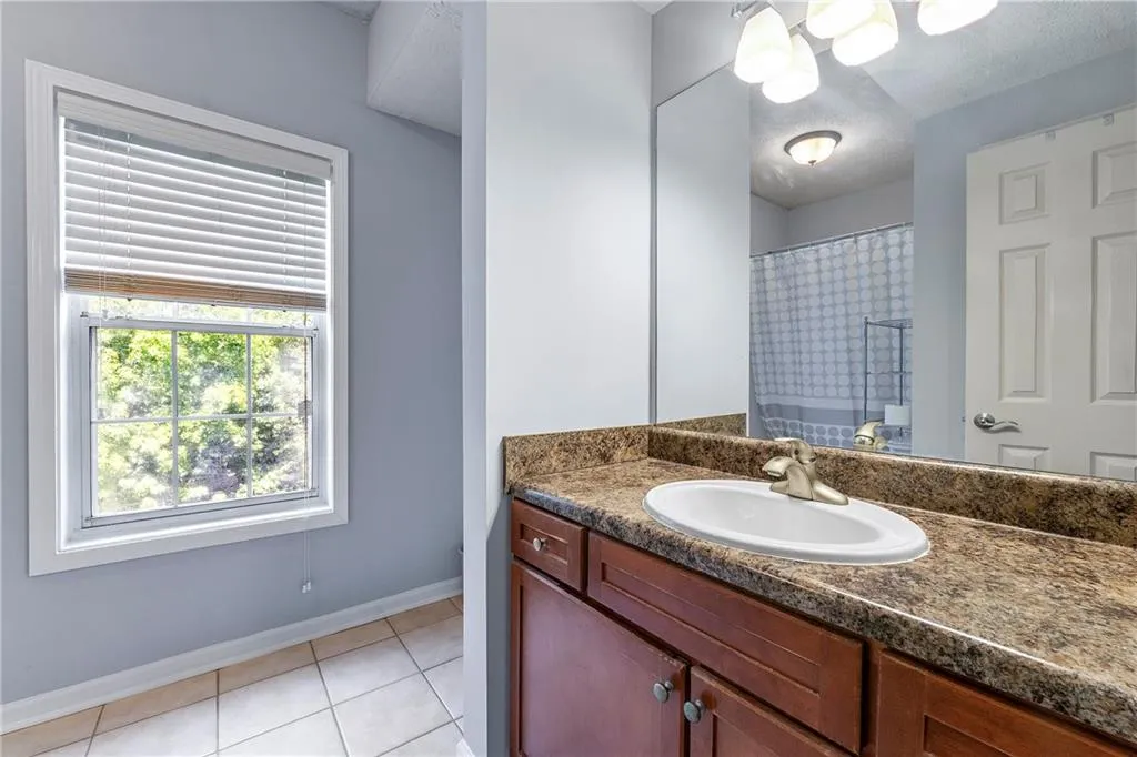 Bathroom with light tile patterned flooring, vanity, and a shower with shower curtain