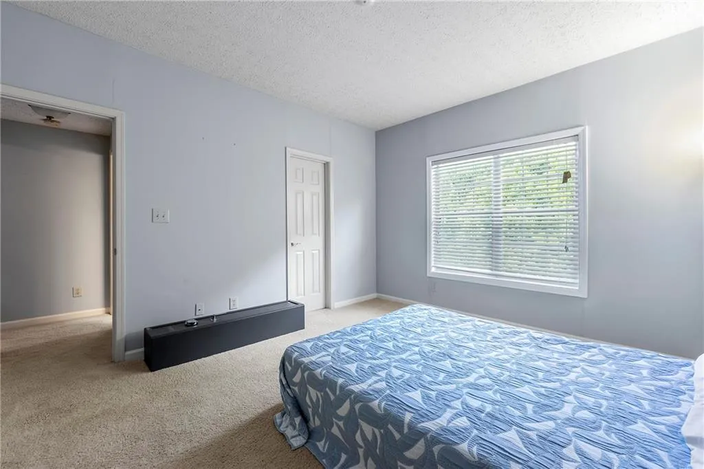 Bedroom with a textured ceiling and light carpet
